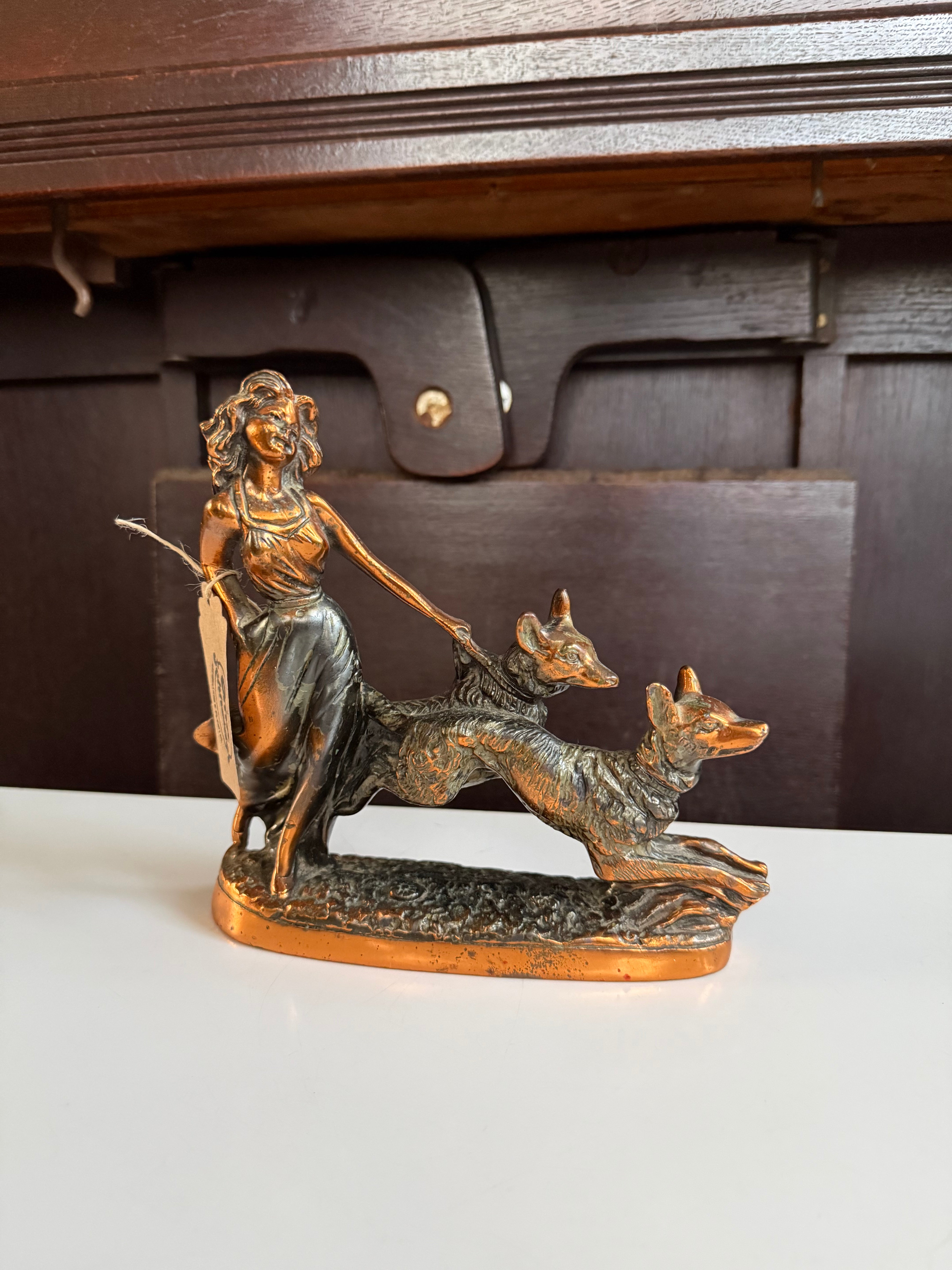 Escultura decorativa em petit bronze representando uma mulher acompanhada por dois cachorros 