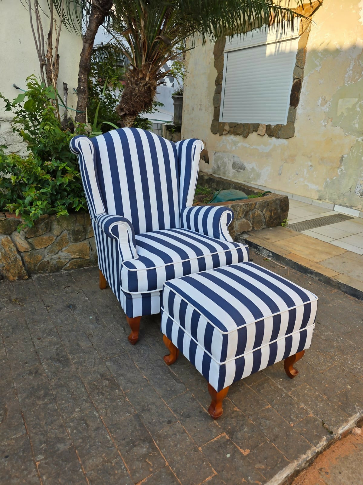 Poltrona bergere estofada e forrada com tecido acquablock listrado branco e azul.