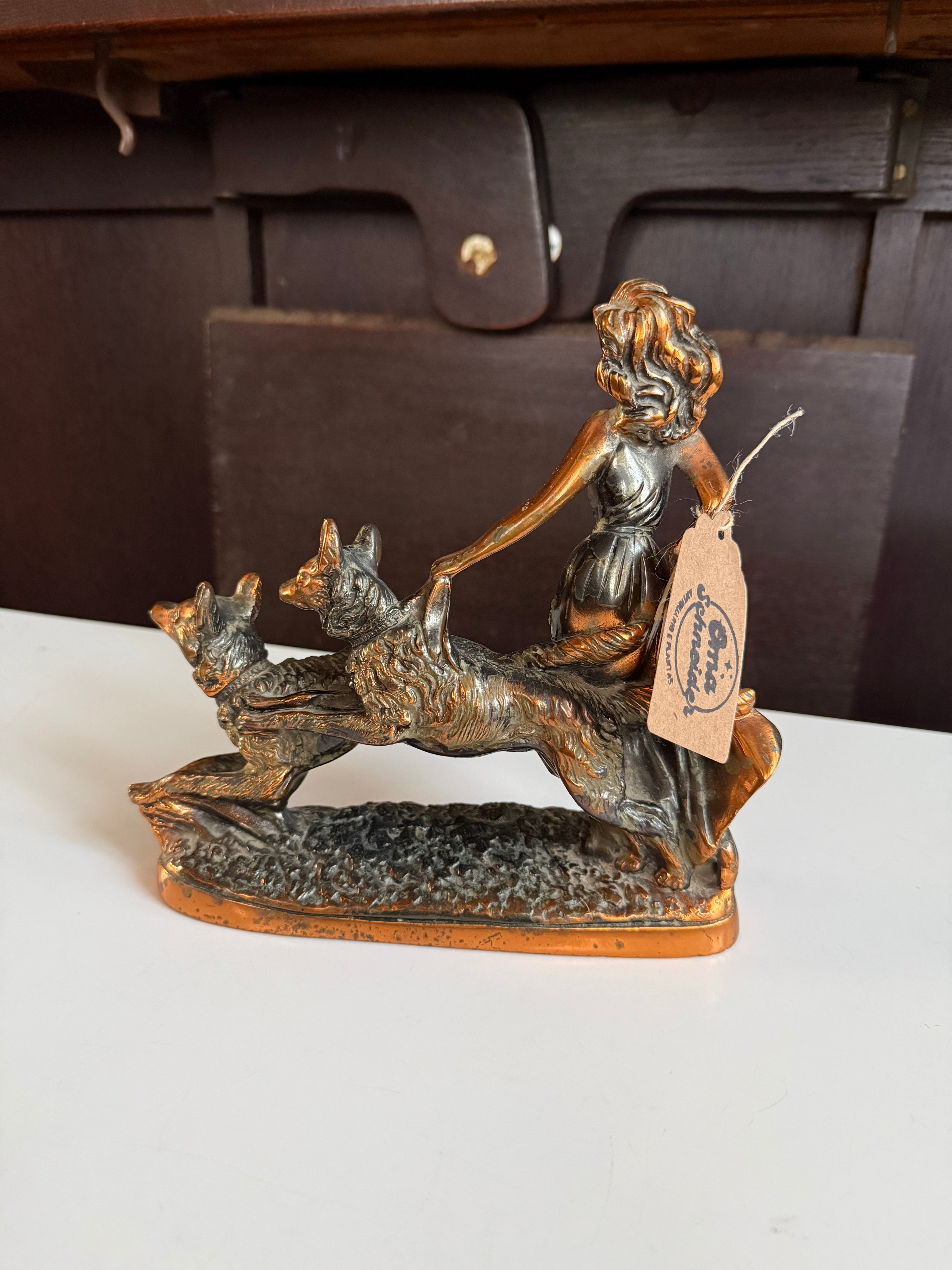 Escultura decorativa em petit bronze representando uma mulher acompanhada por dois cachorros 