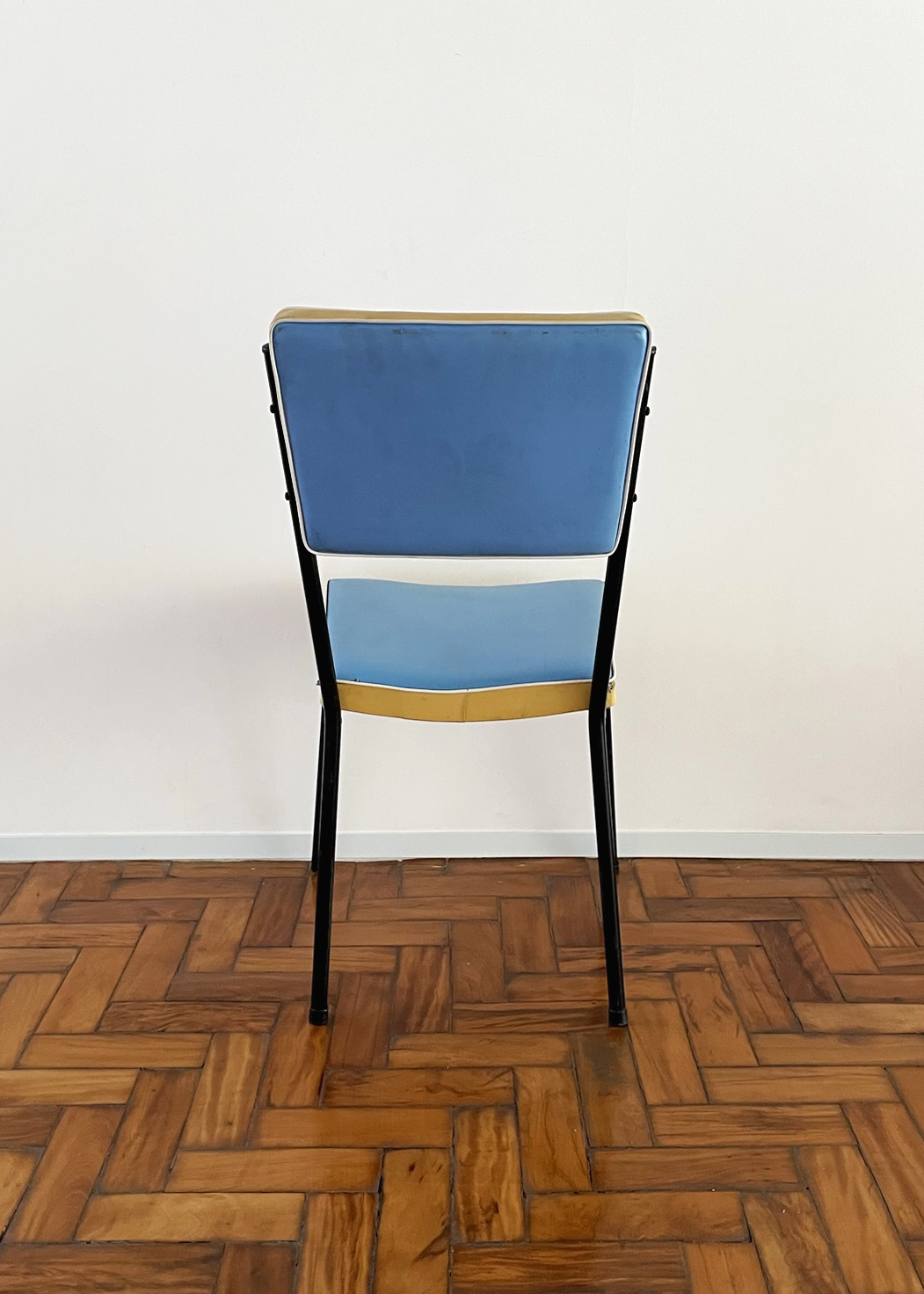 Cadeira cinquentinha. Estofado azul, detalhe creme e estrutura metálica preta.