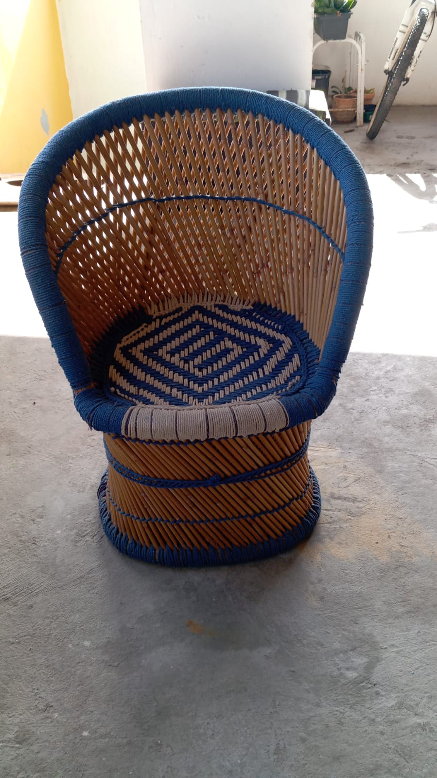 Cadeira arredondada de bambu com tecido crochê azul 