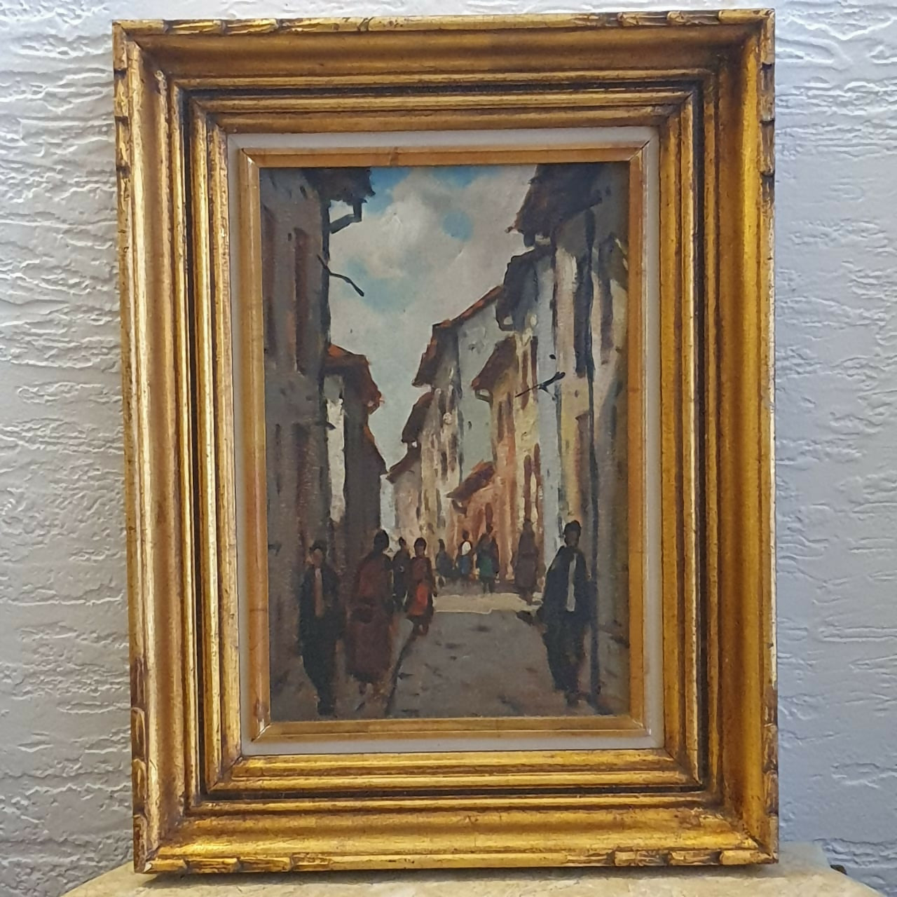 Linda paisagem urbana com casario, em perfeito estado, com moldura de madeira talhada dourada.