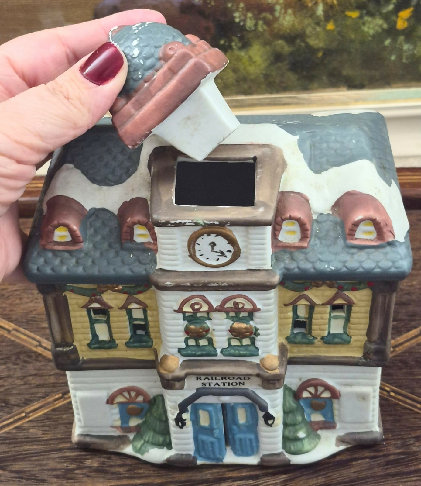 Casinha luminária representando estação de trem vintage, feita em biscuit, com portas, janelas e relógio frontal vazados para iluminação interna.