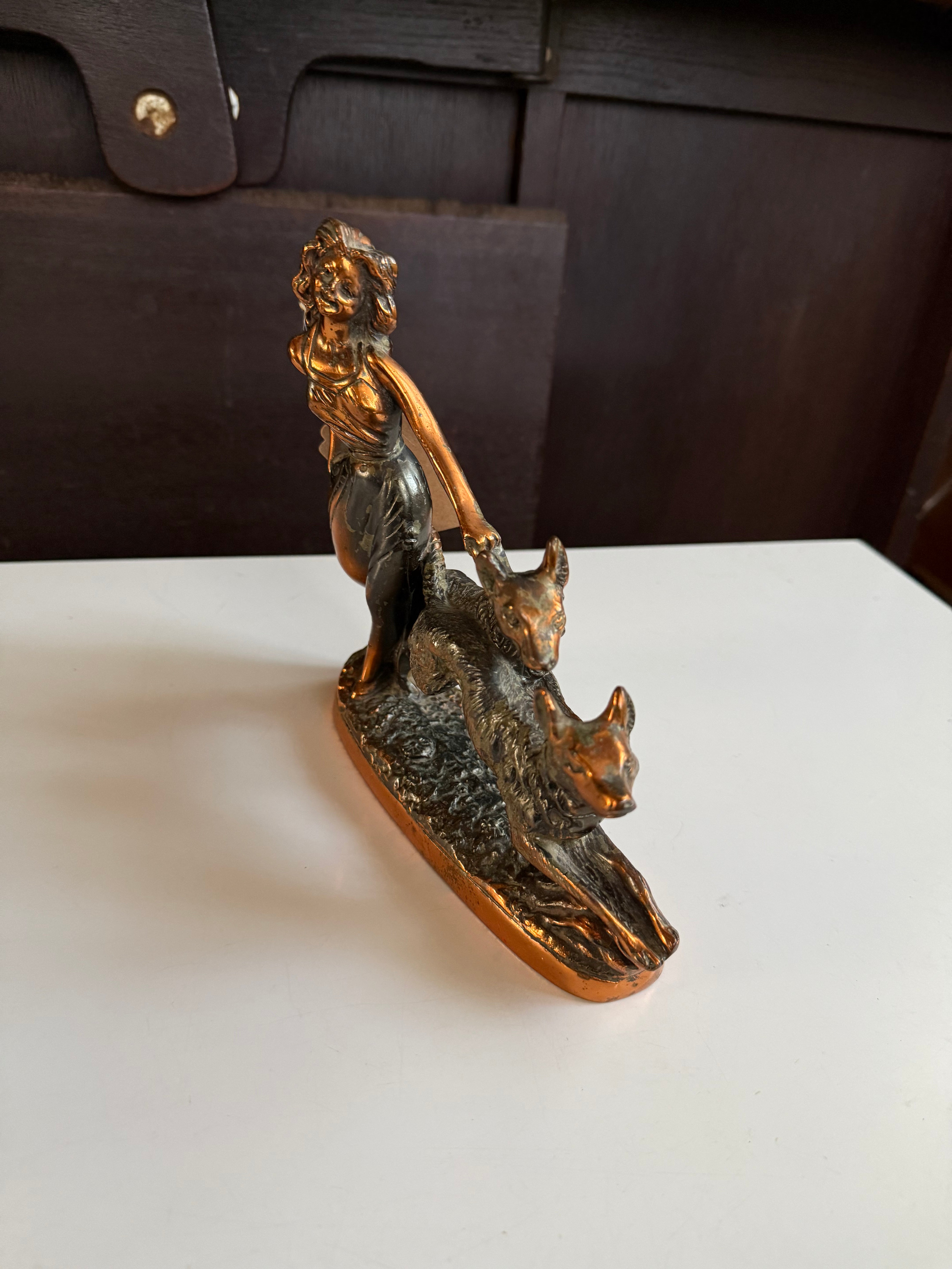 Escultura decorativa em petit bronze representando uma mulher acompanhada por dois cachorros 