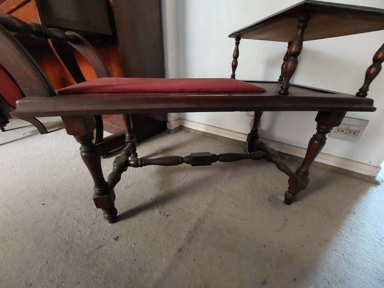 Banqueta de telefone antiga com tecido avermelhado