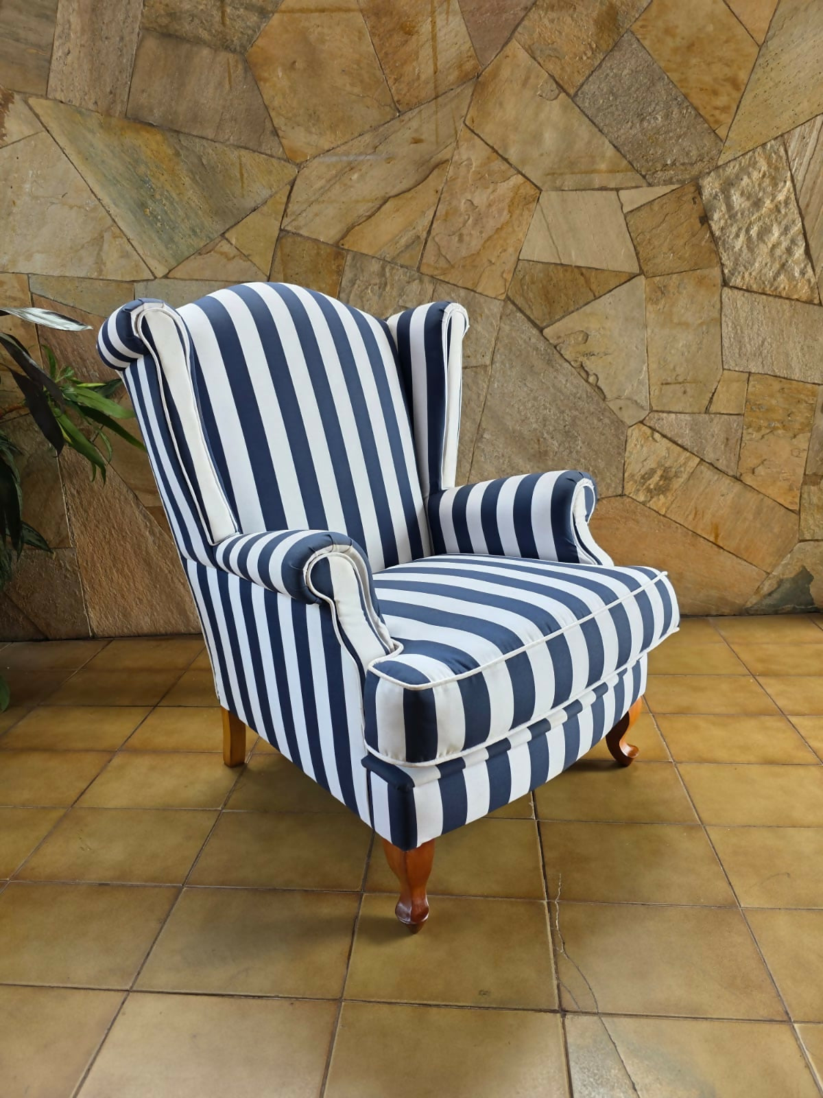 Poltrona bergere estofada e forrada com tecido acquablock listrado branco e azul.