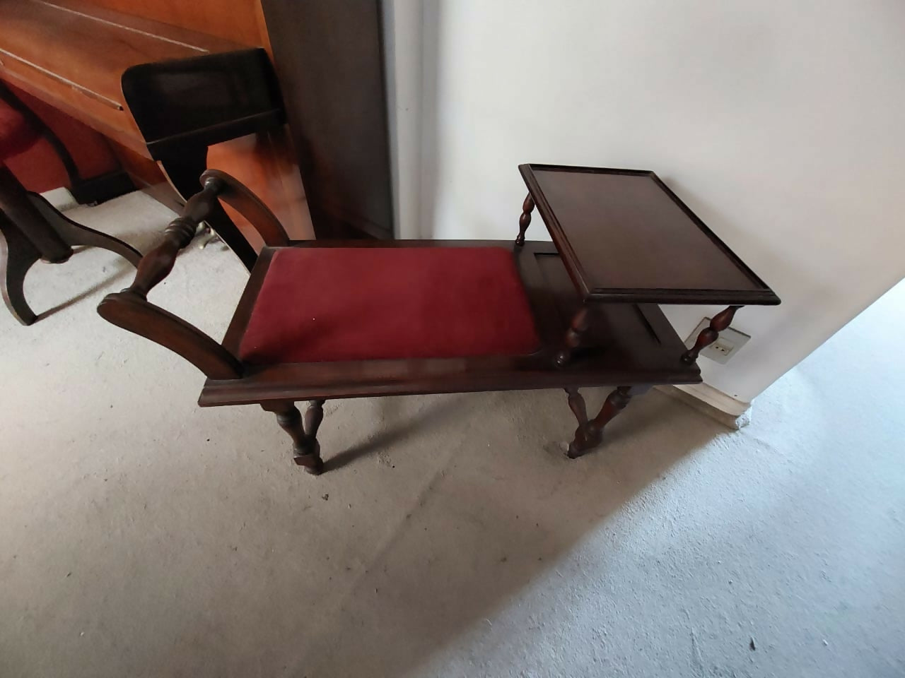 Banqueta de telefone antiga com tecido avermelhado