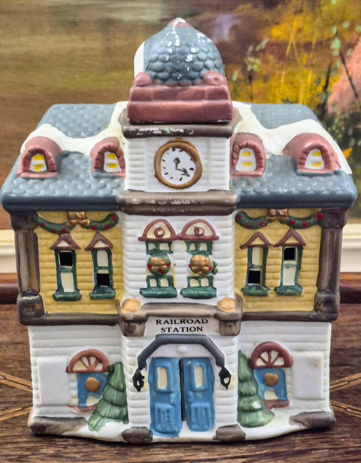 Casinha luminária representando estação de trem vintage, feita em biscuit, com portas, janelas e relógio frontal vazados para iluminação interna.