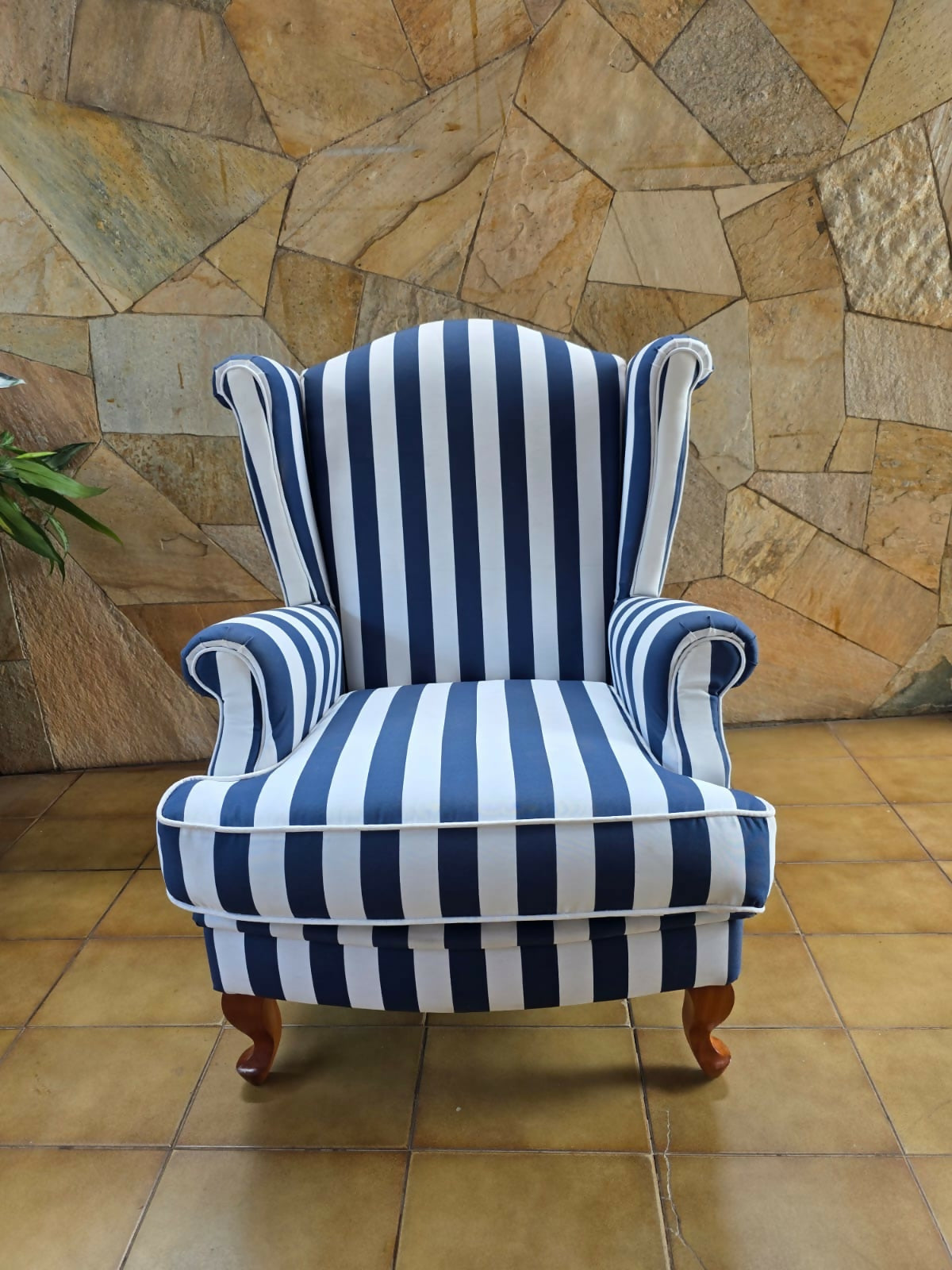 Poltrona bergere estofada e forrada com tecido acquablock listrado branco e azul.