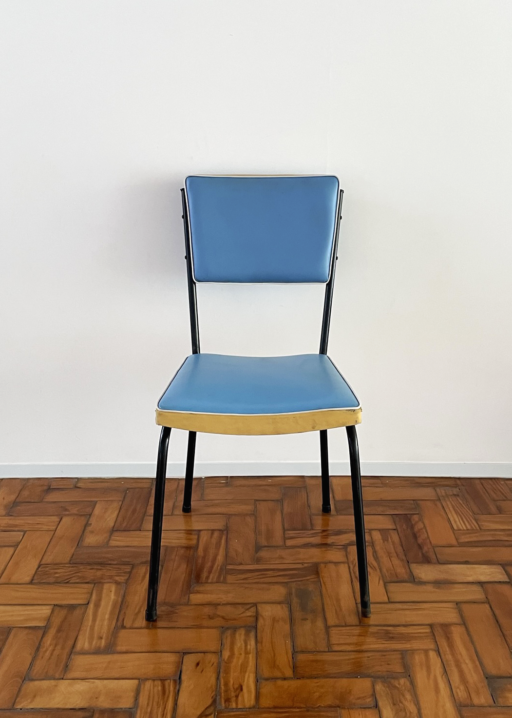 Cadeira cinquentinha. Estofado azul, detalhe creme e estrutura metálica preta.