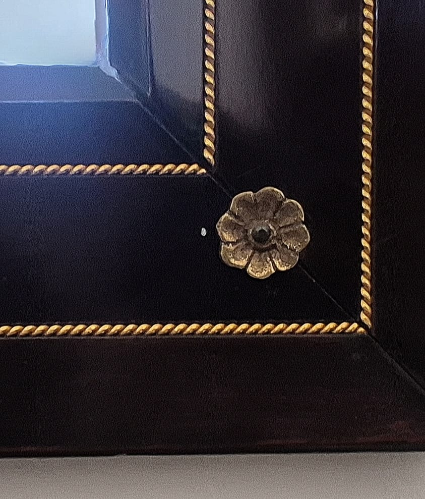 Conjunto composto por um aparador em estilo Luís XV e um espelho de moldura preta.