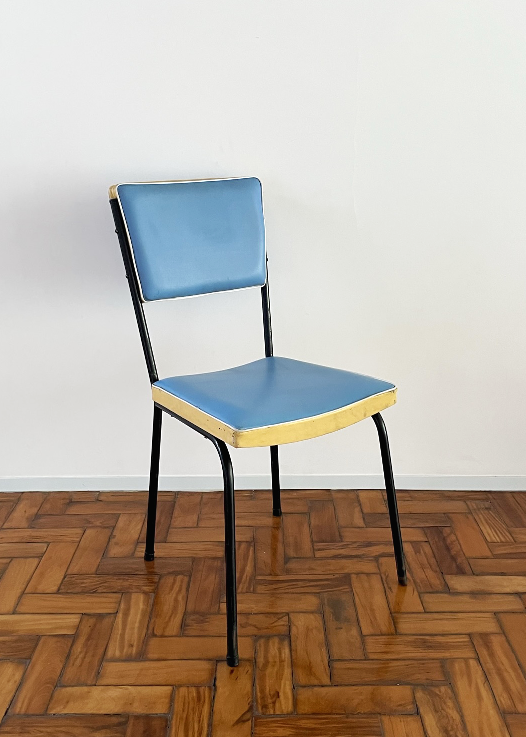 Cadeira cinquentinha. Estofado azul, detalhe creme e estrutura metálica preta.