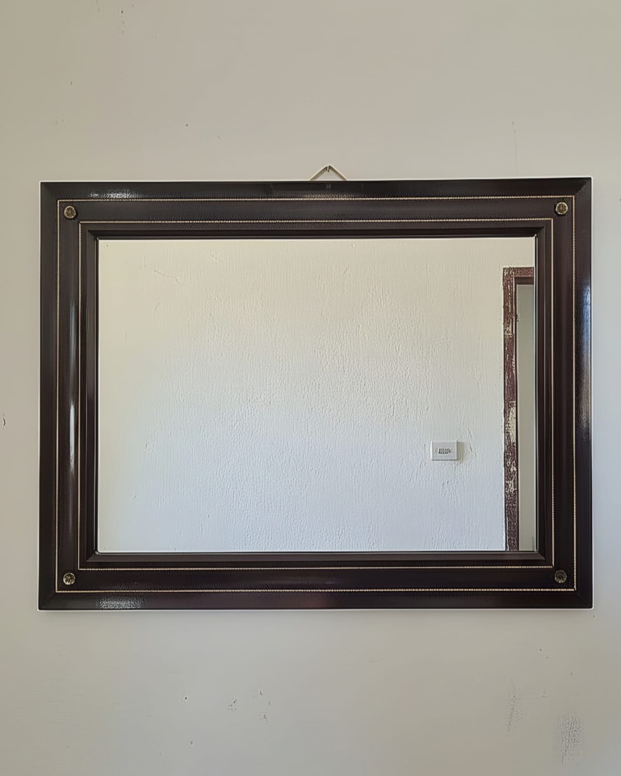 Conjunto composto por um aparador em estilo Luís XV e um espelho de moldura preta.